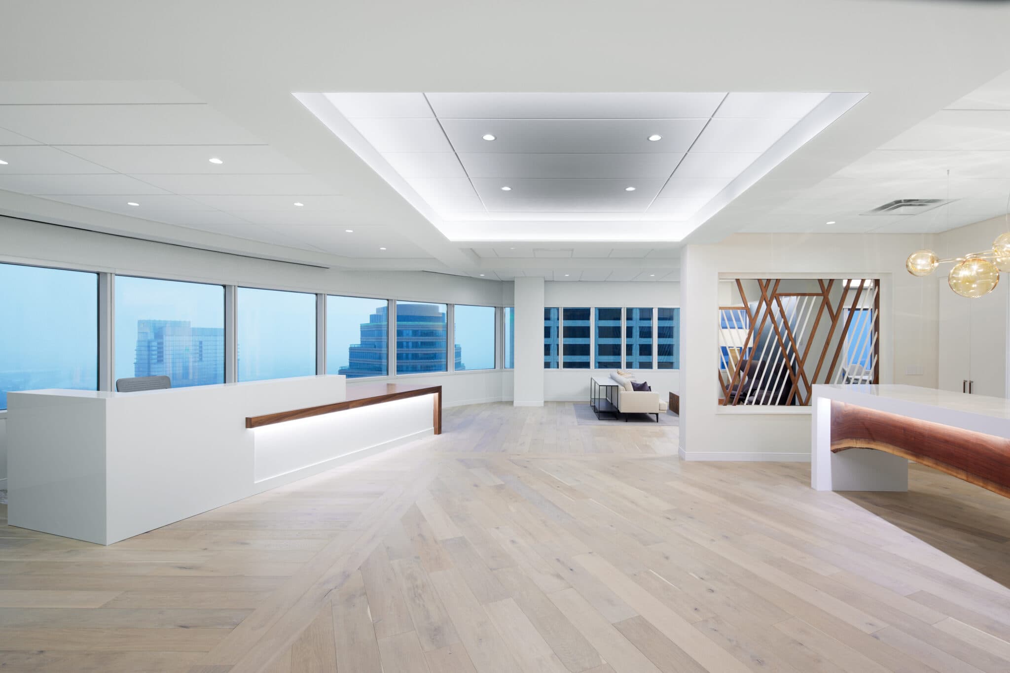 Bright commercial reception area with light wood flooring, glass perimeter walls, and accent lighting