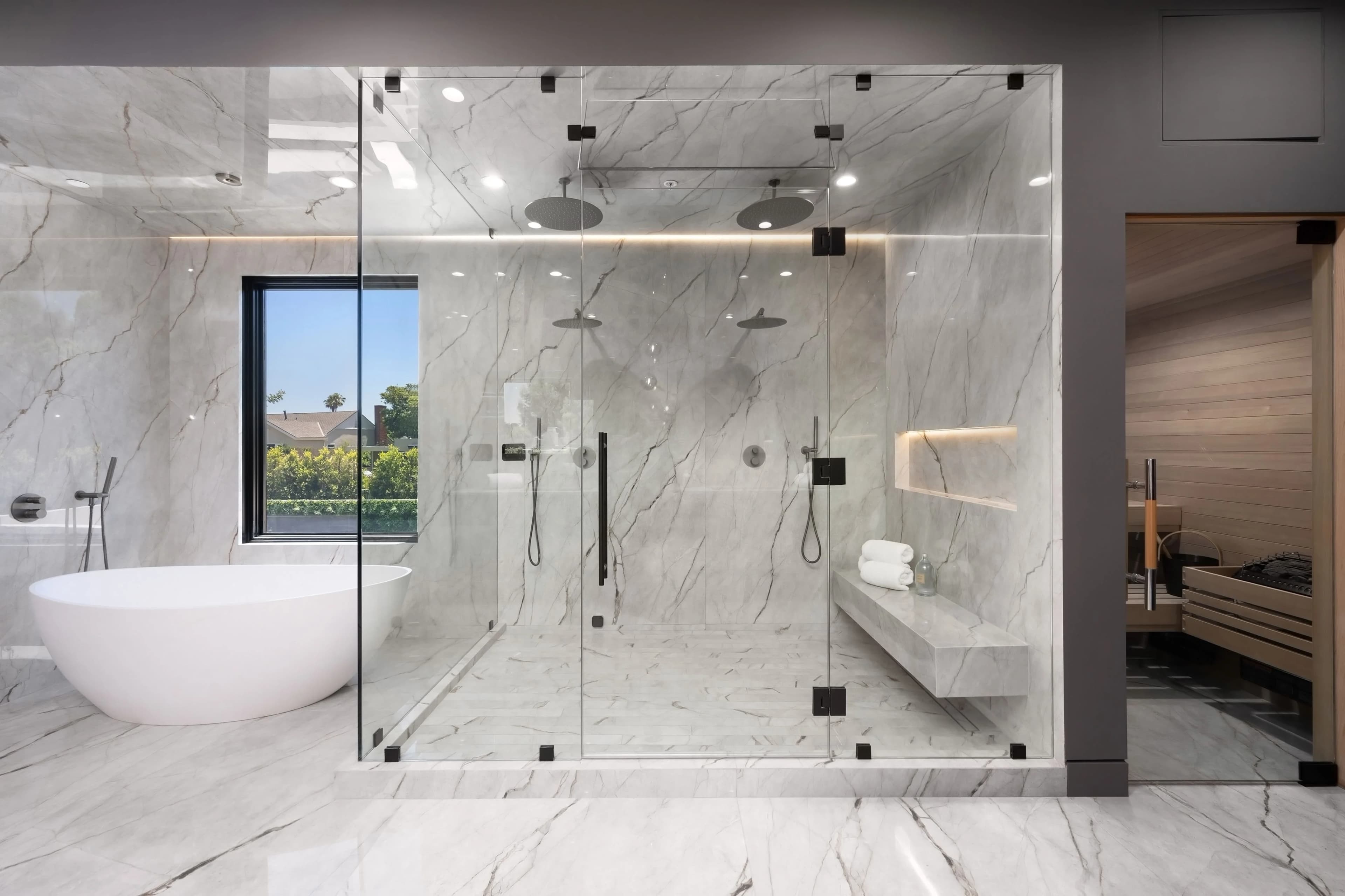 Marble bathroom with glass shower enclosure and freestanding tub